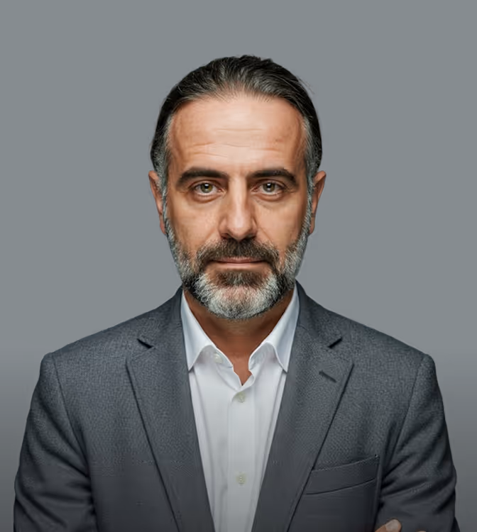 Homem de meia-idade com barba grisalha e cabelo penteado para trás usando terno cinza e camisa branca.